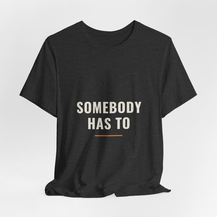 Dark grey heather Somebody Has To t-shirt shown draped, front print visible.