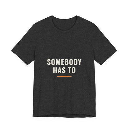 The Somebody Has To design printed on a dark grey heather unisex t-shirt.