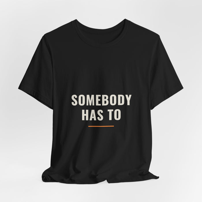Black Somebody Has To t-shirt shown draped, front print visible.