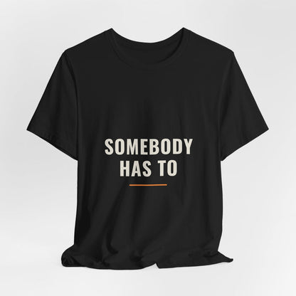 Black Somebody Has To t-shirt shown draped, front print visible.