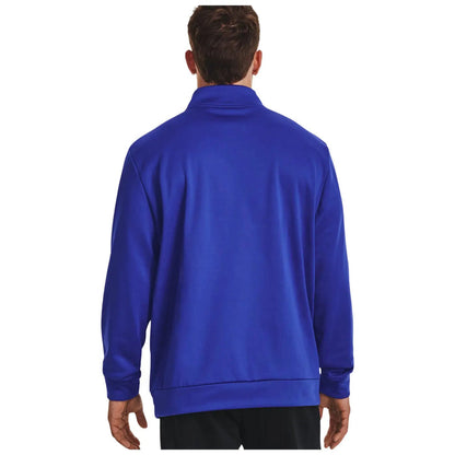 A person wearing a blue long-sleeve jacket stands with their back facing the viewer in a plain white background. The jacket has a high collar and relaxed fit.