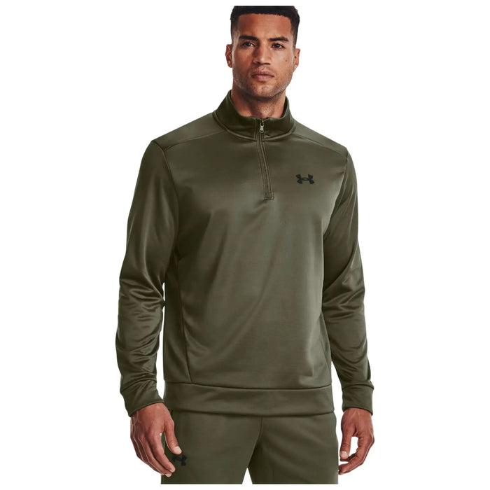 A man wears a green athletic pullover with a zipper and a logo on the chest while standing straight and looking directly at the viewer in a neutral background.